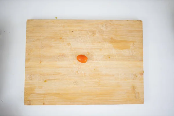 Tomate cereja em uma tábua de corte acima de uma mesa branca — Fotografia de Stock