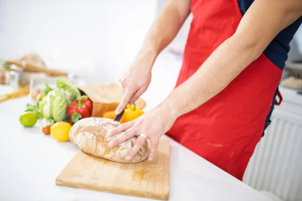 Manos masculinas rebanando pan en una tabla de cortar — Foto de Stock