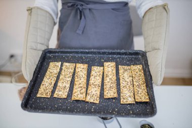 Eldivenli eller siyah bir tepsi İsveç gevreği tutuyor.