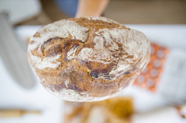 Masadaki malzemelerin üzerinde ekmeği tutan kadın eli.