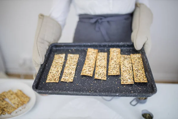 Gloved hands holding a black tray of Swedish crispbread — Stock Photo, Image