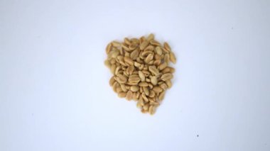 Beyaz masada izole edilmiş küçük bir fıstık yığını.