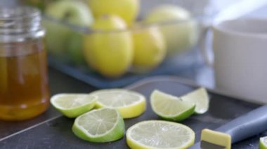 Limon ve limon dilimleri siyah bir tepside bal kavanozunun yanında.