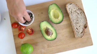 Dilimlenmiş ekmek ve avokadolarla kesme tahtasından tohum topluyorum.