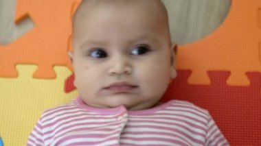 Sevimli bebek renkli bir köpük paspasın üzerinde yatıyor