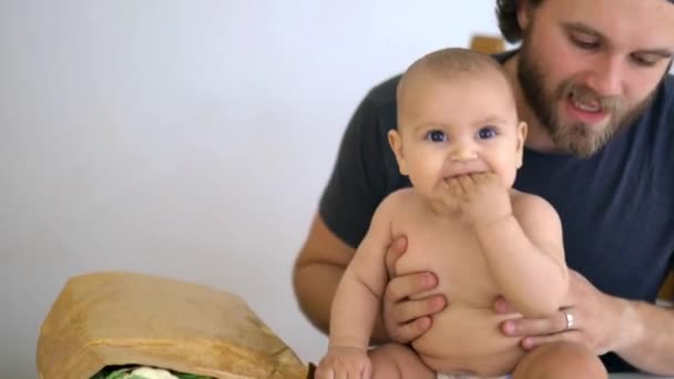 Pai segurando e beijando sua filha bebê acima de uma mesa — Vídeo de Stock