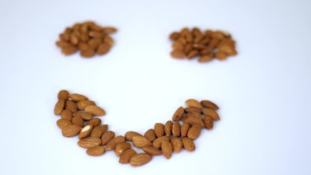 Tumpukan kecil almond dalam bentuk wajah tersenyum di atas meja putih — Stok Video