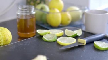 Limon ve limon dilimleri siyah bir tepside bal kavanozunun yanında.