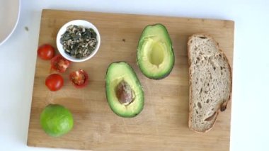 Dilimlenmiş ekmek ve avokadolarla kesme tahtasından tohum topluyorum.
