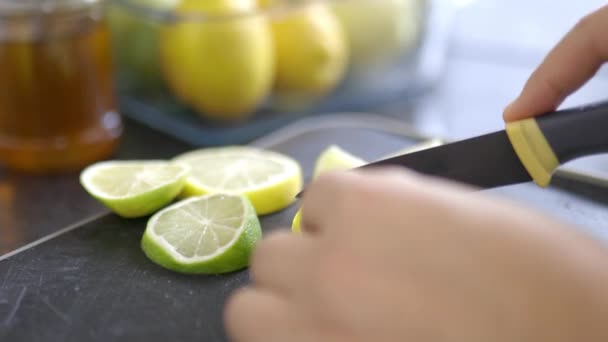 Mãos femininas cortando limões e limas em uma bandeja preta — Vídeo de Stock