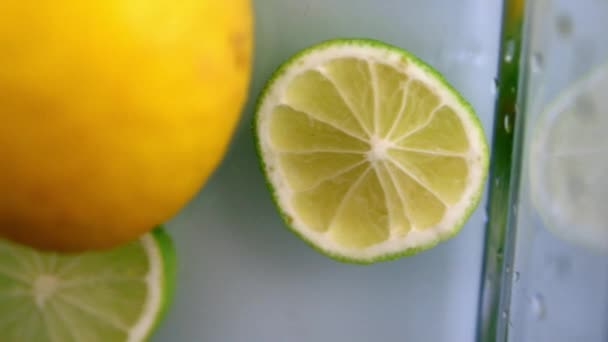 Limetten und Zitronen in Wasser in einem Glasbehälter — Stockvideo