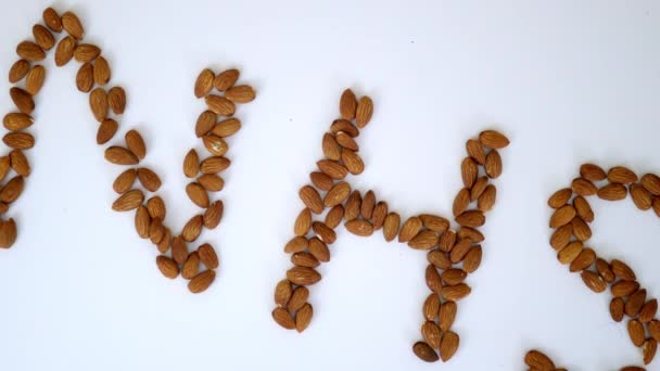 Lettres NHS faites avec des amandes au-dessus d'une table blanche — Video