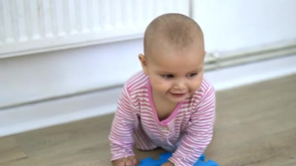 Bayi manis berbaring di lantai kayu dan bermain dengan tikar berwarna-warni — Stok Video