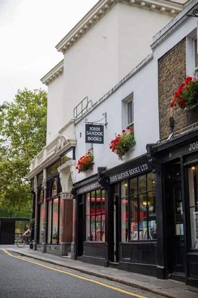 Pencerelerinin dışında kırmızı çiçekli siyah İngiliz kitapçısı