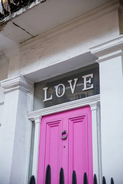 Λέξη αγάπη πάνω από τη ροζ πόρτα ενός λευκού βρετανικού οίκου — Φωτογραφία Αρχείου