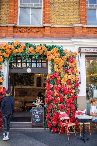 Girişin üzerinde kırmızı ve turuncu çiçekli bir kafe var.