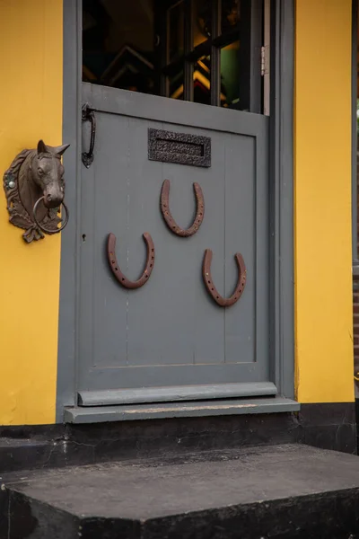 Ferradura e a pequena estátua de uma cabeça de cavalo em uma porta cinza — Fotografia de Stock