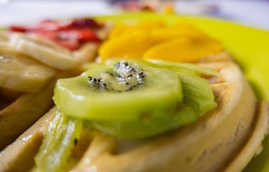 Üstünde meyve dilimleri olan sarı bir tabakta gözleme.