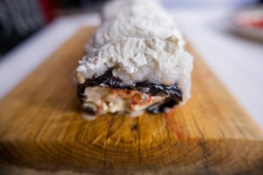 Kesme tahtasındaki beyaz kremayla kaplı suşi ruloları.