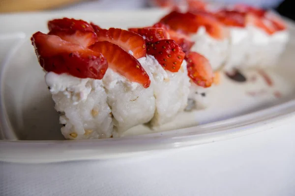 Sushi rohlíky na bílém talíři s jahodovými plátky navrchu — Stock fotografie