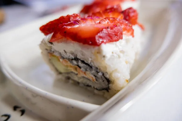 Sushi rohlíky na bílém talíři s jahodovými plátky navrchu — Stock fotografie