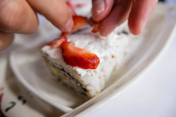 Ruční balení jahodových plátků na sushi rolích nad bílým talířem — Stock fotografie