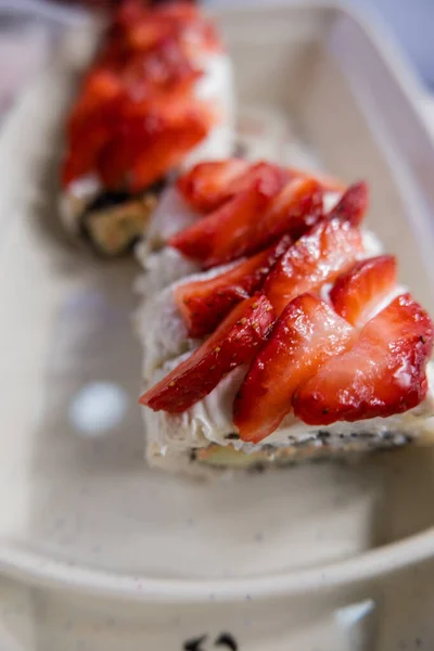 Sushi rohlíky na bílém talíři s jahodovými plátky navrchu — Stock fotografie