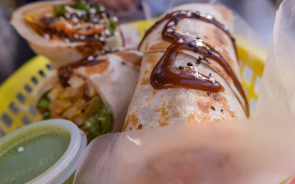 Burritos cubiertos con salsa y semillas en una canasta de plástico —  Fotos de Stock