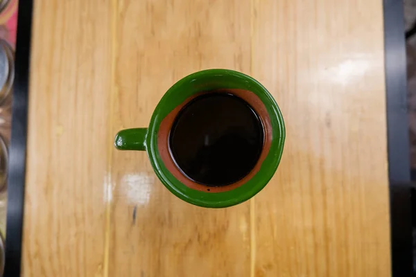 Mexican clay cup filled with coffee on a wooden counter from above — Stock Photo, Image