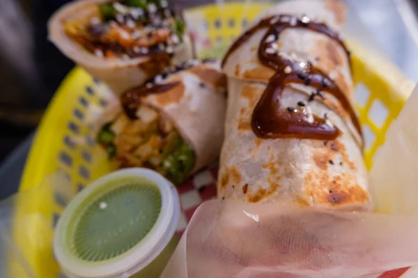 Burritos recouverts de sauce et de graines sur un panier en plastique — Photo