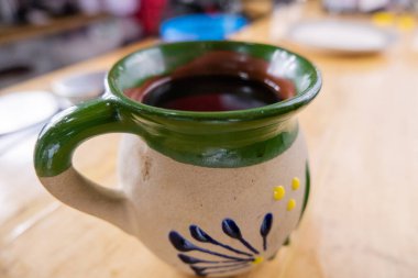 Bulanık arka planı olan ahşap bir tezgahta Meksika kil bardağı.