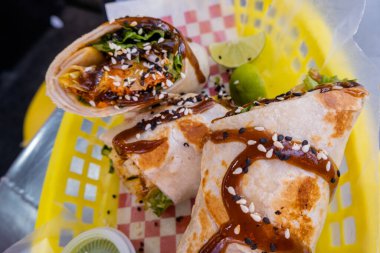 Sosla kaplı burritolar ve plastik bir sepette tohumlar.