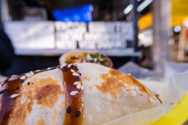 Sosla kaplı burritolar ve plastik bir sepette tohumlar.