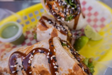 Sosla kaplı burritolar ve plastik bir sepette tohumlar.