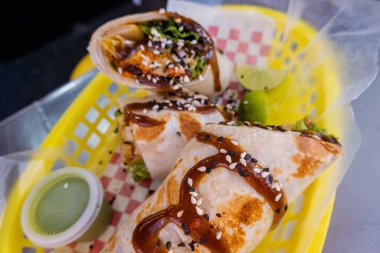 Sosla kaplı burritolar ve plastik bir sepette tohumlar.