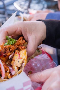 Plastik sepetin üstünde vejetaryen taco tutan bir kadın.