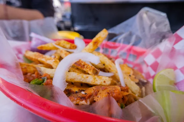 Fries and onions on top of a vegetarian taco on a plastic basket — Stock Photo, Image
