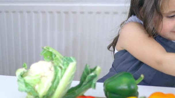 Boldog kislány az asztalnál mosolyog és salátát tart a kezében. — Stock videók