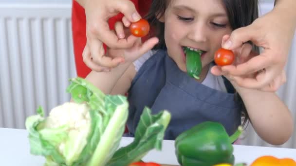 Niña feliz en una mesa jugando con tomates y un pepino — Vídeos de Stock