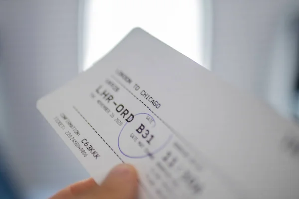 Male hand holding airplane ticket with a window as background