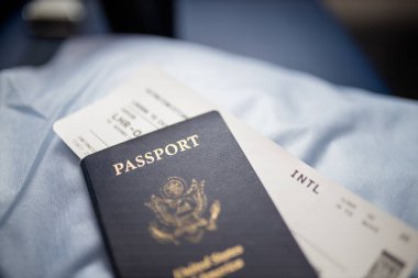 Amerikan pasaportu ve uçak bileti bir koltuğun üstünde.