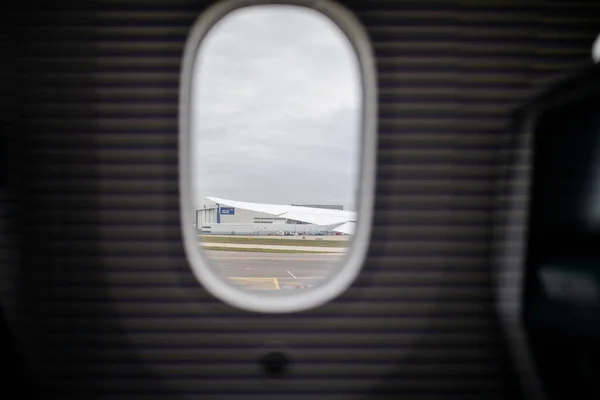 Flygplats och molnig himmel från ett flygplansfönster — Stockfoto