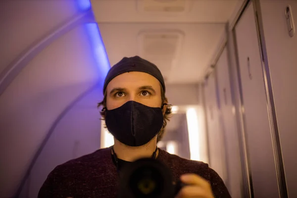 Auto-retrato de um homem usando máscara facial no banheiro do avião — Fotografia de Stock