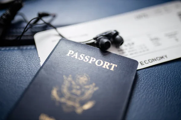 Passaporte americano, bilhete de avião e fone de ouvido acima de um assento — Fotografia de Stock