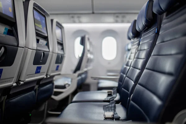 Empty dark blue seats with screens in the back inside an airplane — Stock Photo, Image