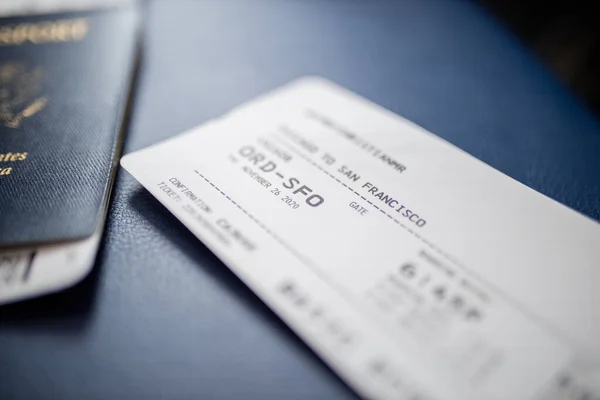 Airplane ticket and American passport above a dark blue seat seat