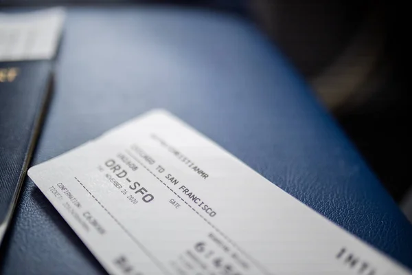 Billete de avión y pasaporte americano encima de un asiento azul oscuro — Foto de Stock