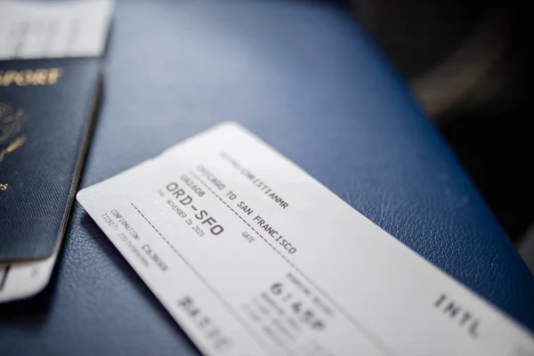 Airplane ticket and American passport above a dark blue seat seat
