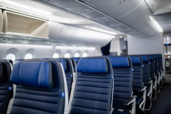 Assentos de avião de passageiros azuis escuros vazios na cabine. — Fotografia de Stock