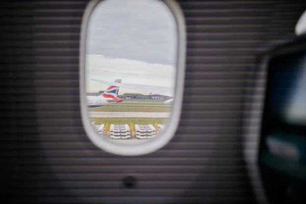 Aeroporto e céu nublado de uma janela de avião — Fotografia de Stock